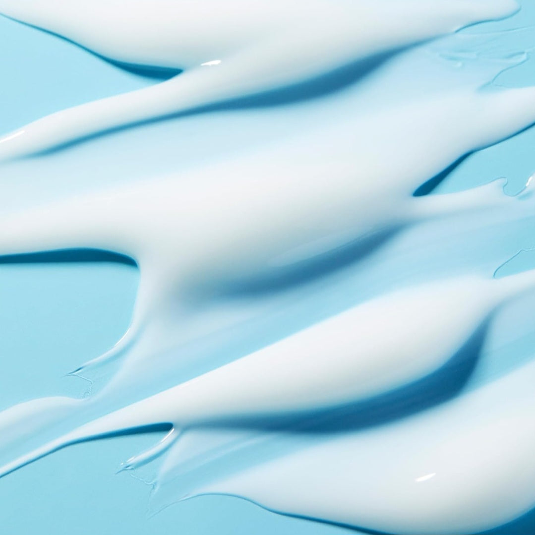 White facial moisturizer in a swirl pattern with aqua color background.