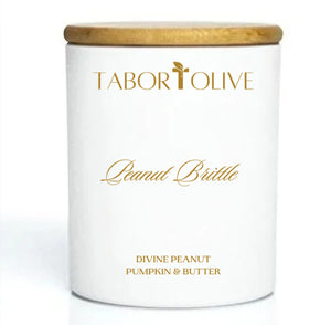 White candle jar with bamboo lid with gold text that says, "Peanut Brittle. Divine peanut pumpkin and butter"