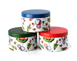 Three holiday print candle tins eith res green and blue lids with snowmen, Christmas trees and ornaments.