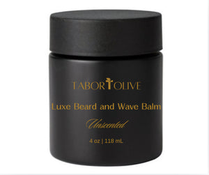 Black glass jar and lid with gold text that says, "Luxe Beard and Wave Balm. All Natural & Non-GMO. Unscented."