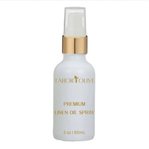 White bottle with gold cap and gold text that says "Tabor and Olive Premium Linen Oil Spray"